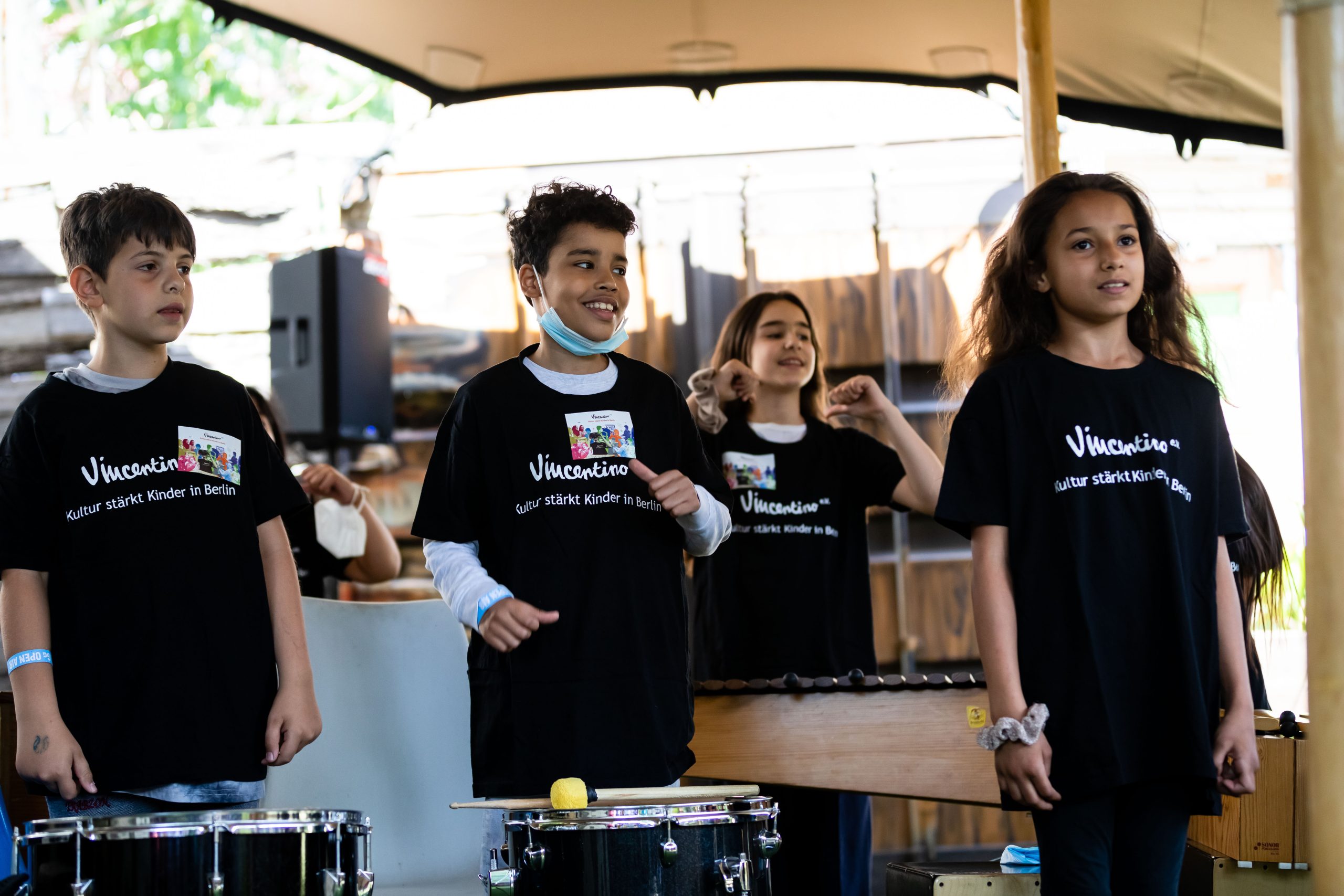 Zu sehen sind vier Schüler*innen der "Kids on Drums" mit schwarzen T-shirts und Trommeln.