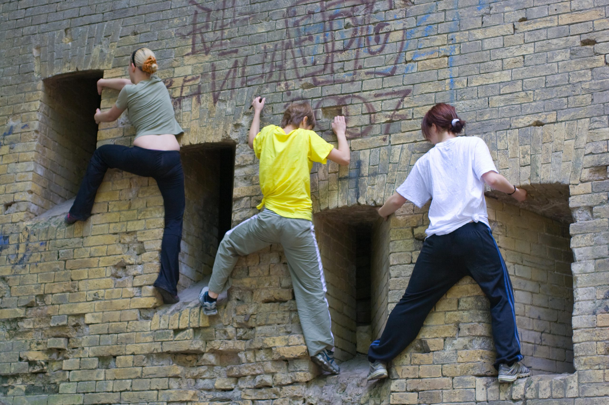 3 Jugendliche klettern an einer Wand lang