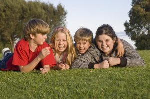 Vier Kinder liegen lachend auf der Wiese