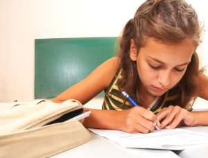 Mädchen lernt im Klassenzimmer mit dem Rücken zur Tafel