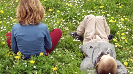 Zwei Kinder sitzen auf einer Wiese